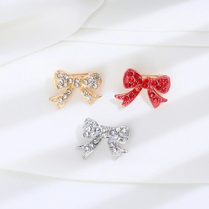 Elegant bow brooch set with rhinestones in gold, silver, and red on white silk background