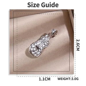 Broche guitare argentée avec cristaux de 2,6cm x 1,1cm posée sur du satin fin