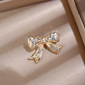 Macro view of golden bow brooch with sparkling rhinestones on satin jewelry box