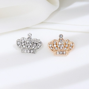 Vue détaillée de broches couronne argent et or avec strass sur tissu de soie blanc
