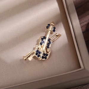 Macro shot of gold violin brooch with blue rhinestones on a jewelry box background