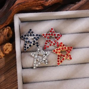 Dettaglio di quattro spille a forma di stella con strass colorati su velluto beige