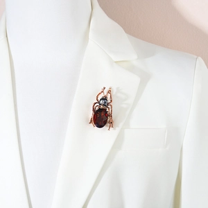 Eleganter Insekten-Anstecknadel mit rotem Tropfenedelstein auf weißem Anzugrevers