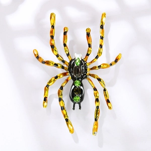 Broche araignée vintage avec strass verts et pattes mouchetées noires sur fond blanc