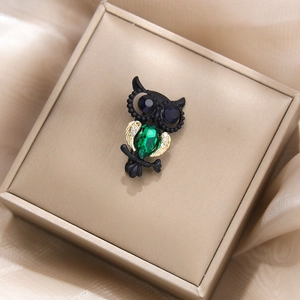 Détail macro de broche hibou avec pierre verte en goutte et yeux en cristal