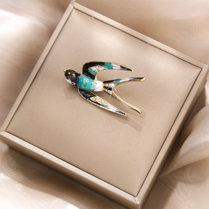 Détail de l'élégante broche hirondelle en émail bleu et cristaux sur du satin