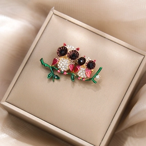 Détail de la broche hibou avec strass et branche émaillée verte en boîte dorée