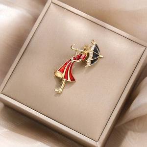 Détail d'une élégante broche fille avec robe rouge tenant un parapluie avec strass