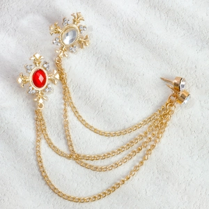 Detail of vintage gold brooch with cross pendants, red rubies, and tiered tassel chains