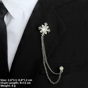 Detail der silbernen Kreuzbrosche mit Strass-Quastenketten am schwarzen Revers