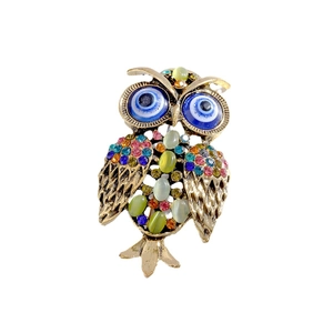 Vintage owl brooch with colorful rhinestones and blue evil eye detail on white background