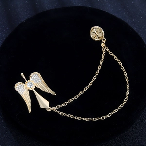 Golden angel wing lapel pin with crystal rhinestones and cross chain on black background