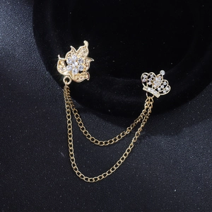 Détail d'une broche couronne et feuille d'érable dorée avec strass et chaînettes