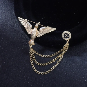 Détail de la broche oiseau dorée ornée de strass et de chaînes métalliques vintage