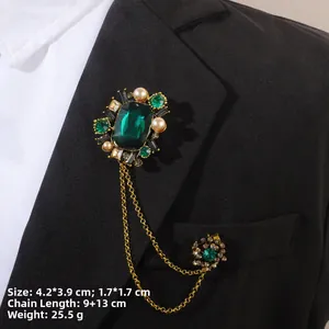 Gros plan d'une broche vintage en émeraude avec chaînes dorées sur revers noir