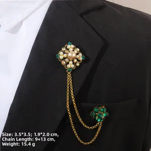 Détail d'une broche baroque avec pierres vert émeraude et chaînes dorées sur un costume