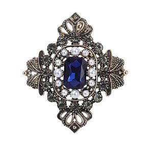 Baroque style brooch with a blue sapphire center, pearls, and vintage gold finish