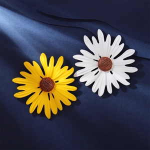 Detailed close-up of yellow and white enamel sunflower pins on a dark blue fabric texture