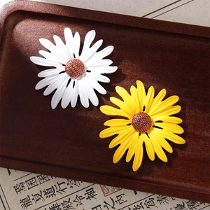 Detailed macro view of white and yellow sunflower enamel brooches on a vintage tray