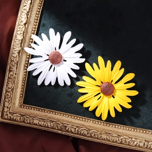 Elegant white and yellow sunflower enamel brooches displayed on a vintage frame