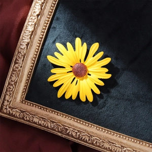 Elegant sunflower enamel brooch with yellow petals on a black velvet background