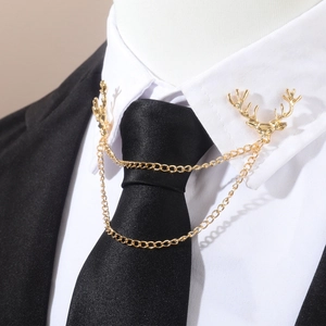 Détail de la broche col tête de cerf dorée avec chaînes sur chemise blanche