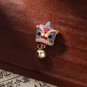 Detail of Chinese style lion dance brooch with rhinestones and a gold bell pendant