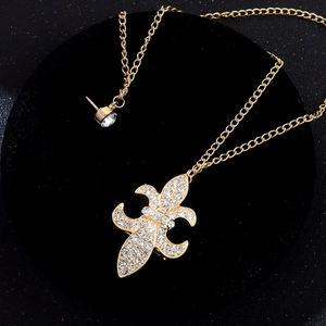 Collier pendentif Fleur de Lys dorée avec strass blancs sur présentoir en velours