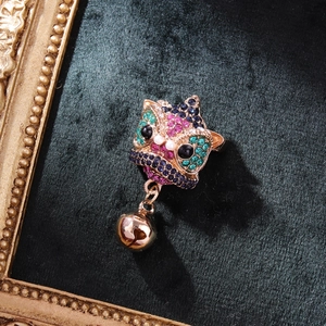 Chinese lion brooch with vibrant rhinestones and bell on green velvet background