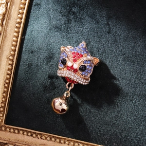 Chinese style lion dance brooch with rhinestones and gold bell on green velvet