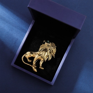 Vintage golden lion brooch with leaf texture and green crystal eyes in a velvet gift box