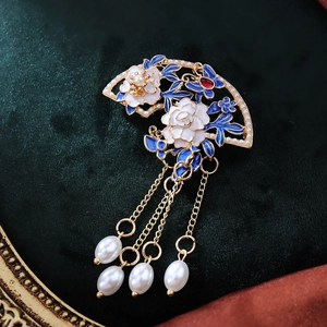Makroaufnahme einer Vintage Fächer-Brosche mit Emaille-Blumen und Perlen-Quasten