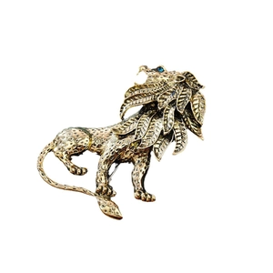 Vintage gold lion brooch with blue gemstone eyes and detailed mane on white background