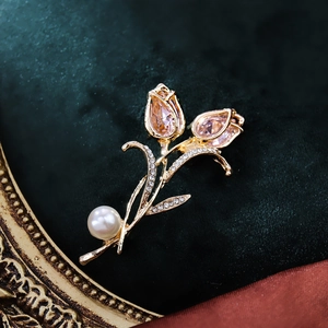 Elegante tulpenbroche met roze kristallen, diamanten en parel op groen fluweel