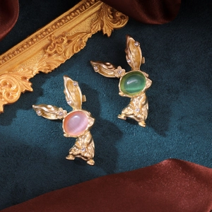 Broches lapin dorées avec pierres œil de chat roses et vertes sur fond en velours vert
