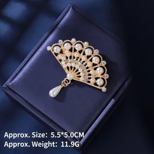 Vintage style hollow fan brooch with pearls and tassels on dark blue silk background
