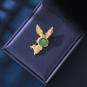 Détail de la broche lapin dorée avec une pierre œil-de-chat verte et des strass étincelants