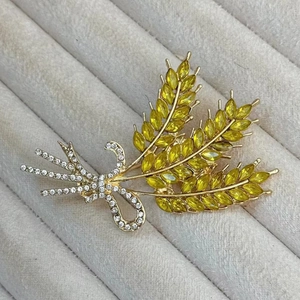 Gouden korenaren broche met gele edelstenen en kristallen op grijs fluweel