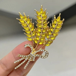 Macro-opname van gouden tarwe broche met gele kristallen en strik met steentjes
