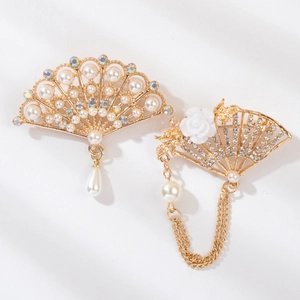 Detailed macro view of two vintage gold fan brooches with pearls and crystal tassels