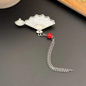 Gros plan détaillé de la broche éventail en argent avec perles et chaînes à pompons