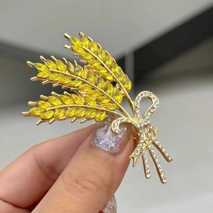 Detailopname van gouden tarwe broche met gele edelstenen en strik met diamantjes