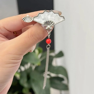 Gros plan sur la broche éventail en argent avec incrustation marbre et pompon