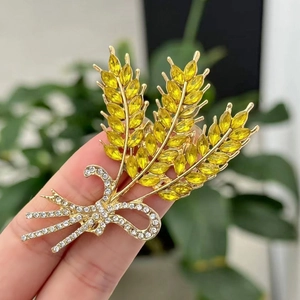 Detailopname van gouden korenaar broche met gele kristallen en een schitterende strik