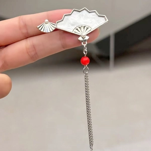 Détail d'une broche éventail argentée avec texture nacre et pendentif en perle rouge