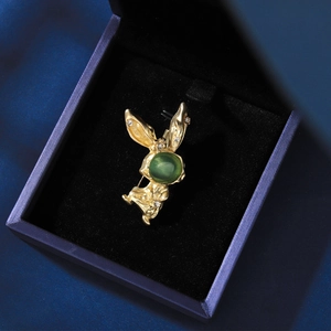 Vue détaillée d'une broche lapin dorée avec opale verte et strass en boîte cadeau
