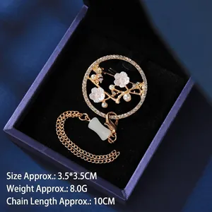 Detailed close-up of a hollow flower brooch with tassel and pearls on velvet box