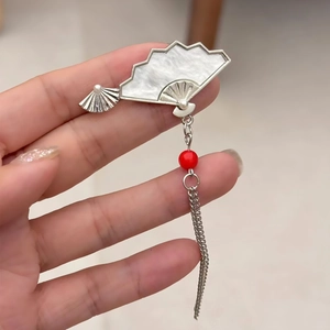Détail de boucles d'oreilles style chinois avec éventail argenté, perle rouge et pompons