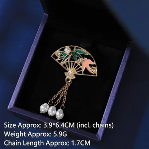 Detailed macro of gold fan brooch with green bamboo leaf and white pearl tassels