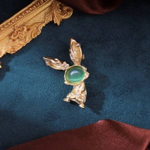 Broche lapin vintage en or avec œil-de-chat vert et strass sur fond de velours bleu
